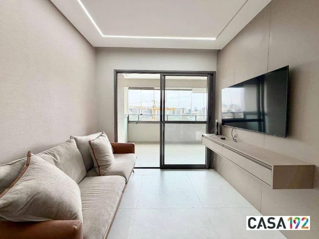 Sala de estar com sofá, painel de TV e acesso à varanda.
