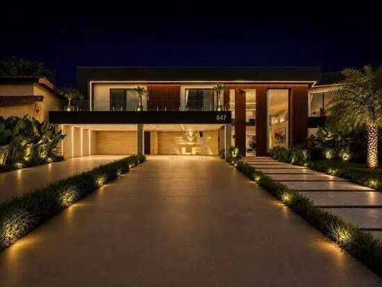 Fachada moderna da casa à noite com iluminação embutida e garagem coberta.